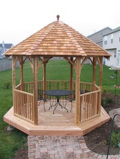 a wooden gazebo sitting on top of a lush green field