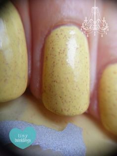 a yellow nail polish with gold flecks on it