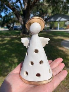 a hand holding a white ceramic angel ornament