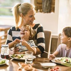 a woman and two children sitting at a table with plates of food in front of them