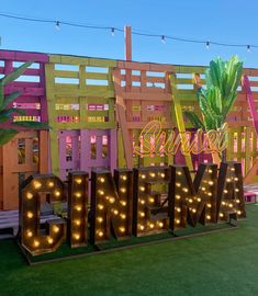 a large neon sign that says cinema in front of a building with palm trees and lights