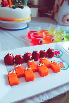 some strawberries and carrots with googly eyes are arranged on a white plate