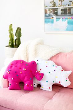 two stuffed animals sitting on top of a pink couch