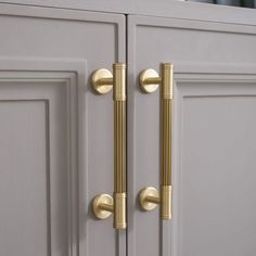 two golden handles are on the front of a gray cabinet