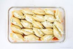 a glass casserole dish filled with ravioli and cream cheese sauce, on a white surface