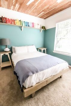 a bed sitting in a bedroom next to a window with bookshelves on the wall