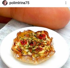 a white plate topped with food on top of a counter next to a person's finger