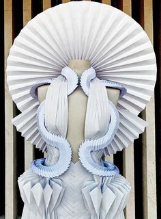 a sculpture made out of white paper with blue ribbons on it's head and shoulders