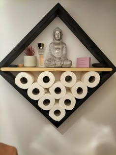 there is a shelf with rolls of toilet paper on it and a buddha statue in the background