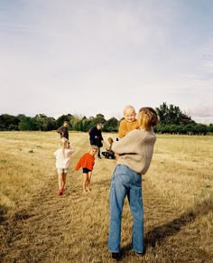 a group of people in a field playing with a frisbee and another person holding a baby