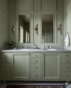 a bathroom with two sinks, mirrors and rug on the floor in front of it