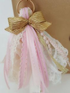 a pink and gold keychain with a bow on it