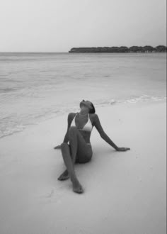 a woman is sitting on the beach in her bathing suit