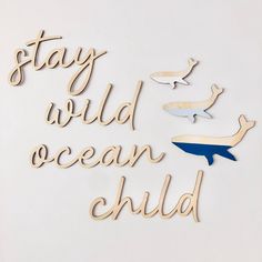 the words stay wild ocean child are cut out of wood and placed on a white surface