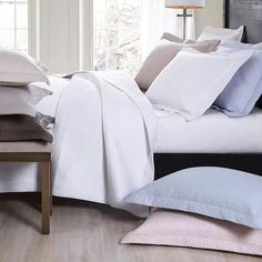 a bed with white sheets and pillows on top of it next to a night stand