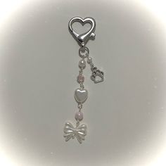 a key chain with charms attached to it on a white surface, in the shape of a heart