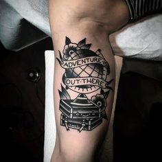 a man's arm with an adventure tattoo on it