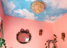 a bathroom with pink walls and blue sky painted on the ceiling