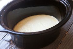 a crock pot filled with bread sitting on top of a wooden table