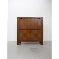 a wooden cabinet sitting on top of a cement floor next to a white wall in an empty room