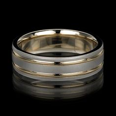 two tone gold and silver wedding ring on black background with reflection in the foreground