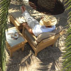 a man laying on top of a chair under a palm tree