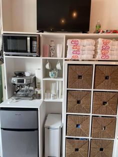 a kitchen area with a refrigerator, microwave and other items on the shelves in front of it