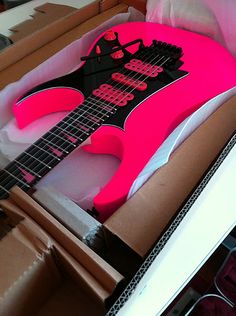 a pink and black guitar in a box