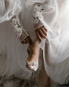 a woman in white dress and high heels with flowers on her feet, wearing clear shoes