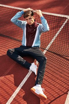 a man sitting on top of a tennis court holding his head with one hand and covering his eyes