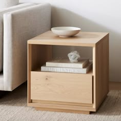 a white bowl sitting on top of a wooden shelf next to a couch and table