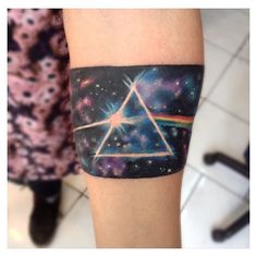 a person with a tattoo on their arm that has a pink floyd triangle in it