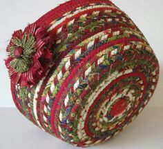 a red and green basket with a flower on it's side sitting on a white surface