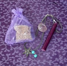 an assortment of items including a wand, necklace and pouch on a purple patterned surface