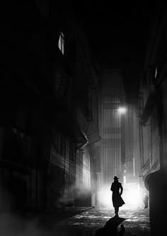 a person standing in the middle of an alley way at night with fog coming from them