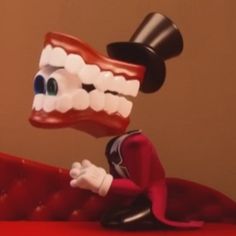 a cartoon character is sitting on a red couch with a toothbrush in it's mouth