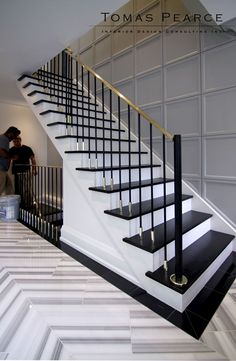 a man standing next to a stair case in a room with white walls and black railings