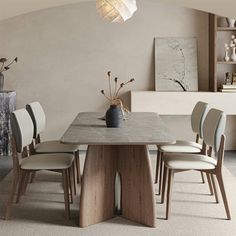 a dining room table with chairs and a vase on the top, in front of a white wall