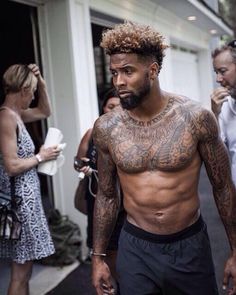 a shirtless man walking down the street with his hair in an afro hairstyle