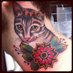 a close up of a person's neck with a cat and flower on it