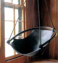 a swing chair hanging from the side of a wooden wall in front of a window