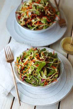 two plates filled with salad on top of a wooden table