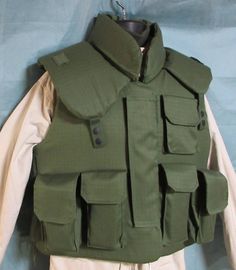 an army green vest with multiple pockets and buttons on the chest, hanging from a hanger