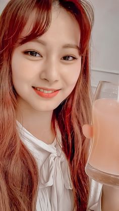 a girl with long red hair holding a glass of milk