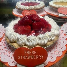 fresh strawberry pie on display in a store window for sale with price tags attached to it