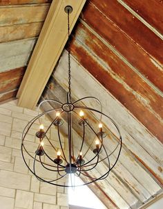 a chandelier hanging from the ceiling in a room with wood paneled walls