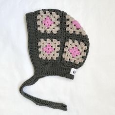 a crocheted hat with pink flowers on it