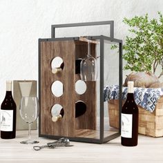 a wine bottle and two glasses on a table next to a wooden box with silverware in it