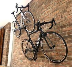 two bikes are mounted to the side of a brick wall