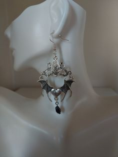 Unveil your daring side with our spellbinding Gothic Bat Earrings. Crafted in the captivating Tibetan silver style, these unique earrings feature intricately designed bats and a raised connector, all adorned with a mesmerizing black teardrop crystal. Embrace the allure of the night with our exquisitely detailed bat-shaped earrings, symbolizing mystery and transformation for those who appreciate the enigmatic. Each pair of Gothic Bat Earrings is meticulously handcrafted with skill and passion, ensuring a high level of artistry and quality. Their darkly stylish and bold design allows them to seamlessly complement various outfits, from casual wear to formal attire. For those seeking an accessory that stands out from the crowd, our Gothic Bat Earrings are the perfect choice to draw attention a Elegant Winged Metal Jewelry, Gothic Silver Metal Earrings, Silver Gothic Metal Earrings, Gothic Silver Dangle Earrings, Gothic Silver Pierced Earrings, Gothic Sterling Silver Earrings For Parties, Gothic Pierced Jewelry For Party, Silver Witchy Earrings For Party, Silver Gothic Dangle Earrings